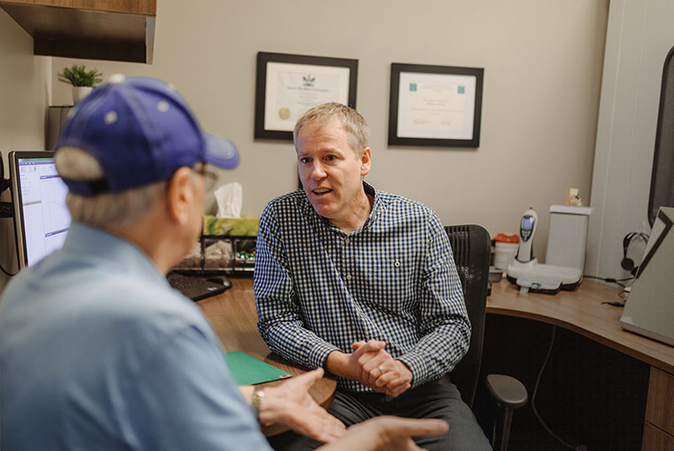 Andrew Sharpe in office speaking to a patient